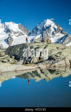 Reflexion der Wanderer unter Piz Bernina und Piz Rosbeg. Fuorcla Surlej, Silvaplana, Berniner Alpen, Graubünden, Schweiz. Stockfoto