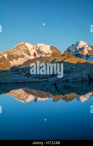 Reflexion der Wanderer unter Piz Bernina und Piz Rosbeg. Fuorcla Surlej, Silvaplana, Berniner Alpen, Graubünden, Schweiz. Stockfoto