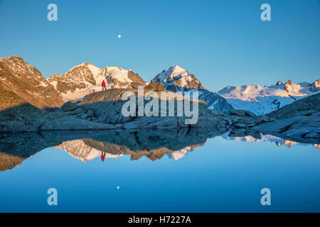 Reflexion der Wanderer unter Piz Bernina und Piz Rosbeg. Fuorcla Surlej, Silvaplana, Berniner Alpen, Graubünden, Schweiz. Stockfoto