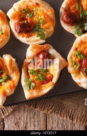 Muffins mit Wurst, Käse und Zwiebel hautnah in Auflaufform legen. vertikale Ansicht von oben Stockfoto