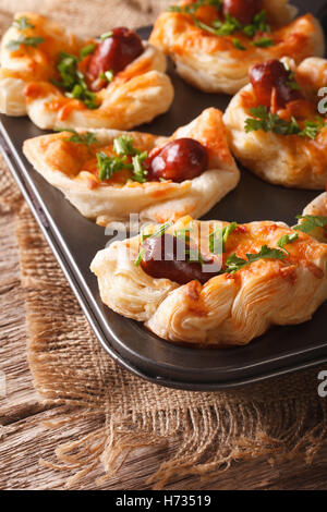 Frisch gebackenen Blätterteig Brötchen mit Wurst, Käse und Zwiebel Makro in die Auflaufform. Vertikal Stockfoto