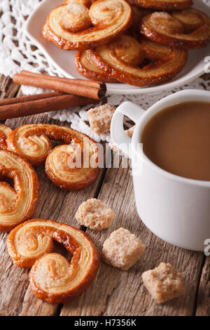 Kekse aus Blätterteig Palmiers und Kaffee mit Milch Nahaufnahme auf einem Tisch, vertikale Stockfoto
