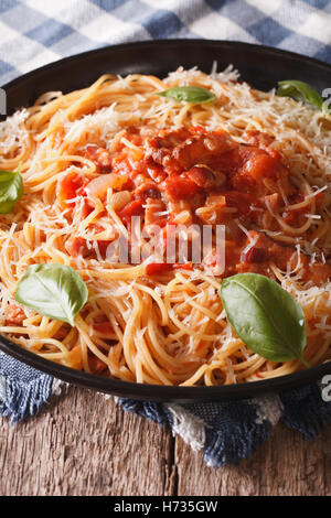 Amatriciana Spaghetti mit Käse und Basilikum Nahaufnahme auf einem Teller auf den Tisch. vertikale Stockfoto