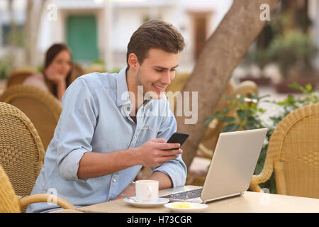 Selbstständiger Mann arbeitet mit einem Laptop und ein Handy in einem restaurant Stockfoto