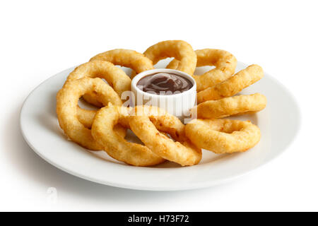 Haufen von tiefen gebratenen Zwiebeln oder Calamari Ringe mit Barbecue-Dip auf weißen Teller. Stockfoto