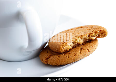 Detail der zwei Ingwer Kekse, eine in der Mitte, mit Tasse und Untertasse gebrochen. Weißen Hintergrund. Stockfoto