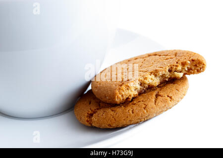 Detail der zwei Ingwer Kekse, eine in der Mitte, mit Tasse und Untertasse gebrochen. Weißen Hintergrund. Stockfoto