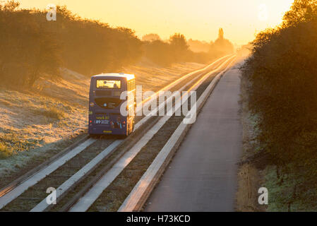 Über, Cambridgeshire UK, 2. November 2016.  Eine geführte Bus-Köpfe in Richtung Cambridge als die Sonne steigt über die Gleise auf eine klare, gestochen scharfe, frostigen Herbstmorgen. Die klare Luft und die ersten Frost im Herbst dieses Jahres in den Osten des Vereinigten Königreichs Schuppen einen goldenen Schimmer auf die Morgen pendeln. Kredit Julian Eales/Alamy Live-Nachrichten Stockfoto