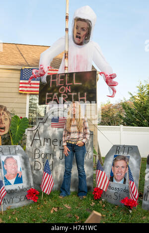 Bellmore, New York, USA. 2. November 2016. EILEEN FUSCALDO, Donald Trump Unterstützer, steht auf einem Friedhof-Anzeige in ihrem Vorgarten mit einem großen Hillary Clinton Geist mit "Hell on Earth'' Schild drohend über dem Kopf, und Grabsteine mit Fotos der Amerikaner in Bengasi getötet. Ihr Hof hatte viele Schilder und Disaplys zur Unterstützung der republikanische Präsidentschaftskandidat, D. J. Trump, und gegen demokratische H. R. Clinton. Bildnachweis: Ann Parry/ZUMA Draht/Alamy Live-Nachrichten Stockfoto