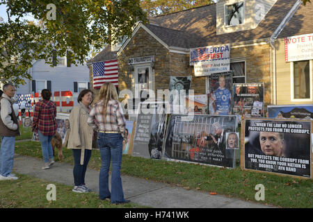 Bellmore, New York, USA. 2. November 2016. EILEEN FUSCALDO, auf der rechten Seite, von hinten gesehen ist im Gespräch mit Nachbarn und andere vor ihrem Haus, mit Zeichen gegen demokratische Präsidentschaftskandidatin Hillary Clinton und zur Unterstützung der republikanischen Donald Trump. Sie sind vor ein Mock-up-Foto von Clinton im Gefängnis. Bildnachweis: Ann Parry/ZUMA Draht/Alamy Live-Nachrichten Stockfoto