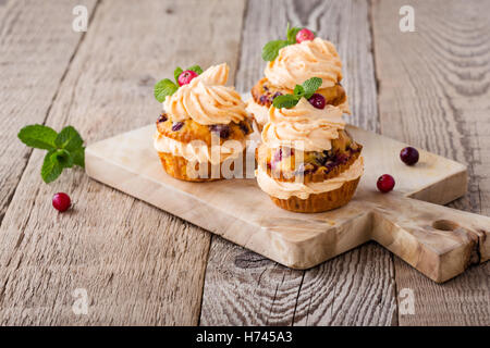 Hausgemachte Herbst Cranberry Kürbis Muffins mit Frischkäse-Glasur auf rustikalen Holztisch Stockfoto