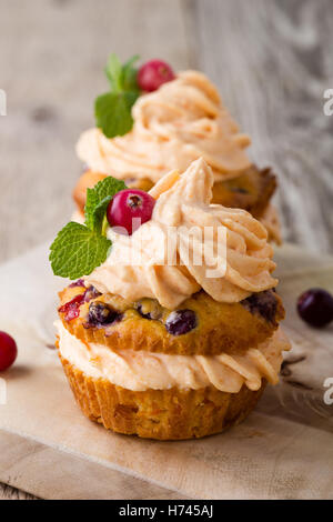 Hausgemachte Herbst Cranberry Kürbis Muffins mit Frischkäse-Glasur auf rustikalen Holztisch Stockfoto