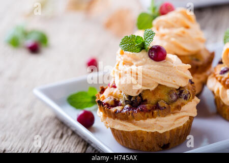 Hausgemachte Herbst Cranberry Kürbis Muffins mit Frischkäse-Glasur auf rustikalen Holztisch Stockfoto