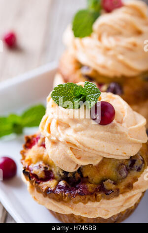 Hausgemachte Herbst Cranberry Kürbis Muffins mit Frischkäse-Glasur auf rustikalen Holztisch Stockfoto