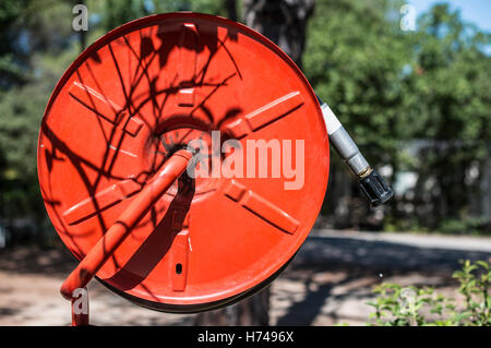 Feuerlöscher in einem Garten. Bäume und Häuser Stockfoto