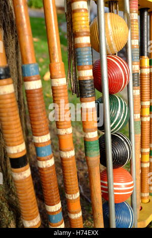 Gut gebrauchter Krocketsatz aus Holz, der draußen auf einem Sommerrasen steht und dessen Kugeln und Schlägel ordnungsgemäß in seinem Holster aufbewahrt werden. Stockfoto