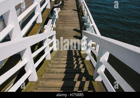 Holzstufen einen Pier mit einem weißen Zaun und das Meer nahe bei ihm. Stockfoto