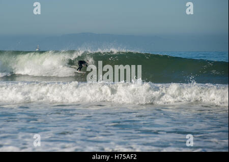 Surfer in schwarzen Neoprenanzug Reiten ein Medium sized Welle links. Stockfoto