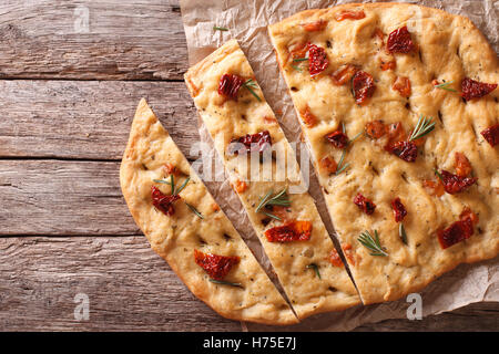 In Scheiben geschnitten Brot italienische Focaccia mit getrockneten Tomaten und Rosmarin auf dem Tisch. horizontale Ansicht von oben Stockfoto