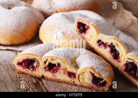 Schneiden Sie Ensaimada Brötchen mit Beeren und Puderzucker close-up auf dem Tisch. horizontale Stockfoto