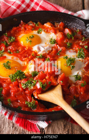 Shakshuka Spiegeleier mit Tomatensauce hautnah in einer Pfanne erhitzen. Vertikal Stockfoto