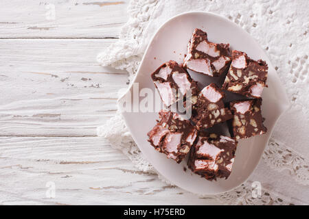 Schokoladenkuchen steiniger Weg mit Marshmallow und Muttern Nahaufnahme auf einem Teller auf den Tisch. horizontale Ansicht von oben Stockfoto