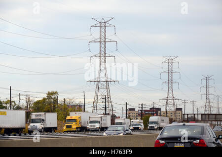 Hochspannungsleitungen entlang einer Autobahn gefüllt mit Sattelschlepper in der Nähe von Elizabeth, New Jersey. Stockfoto