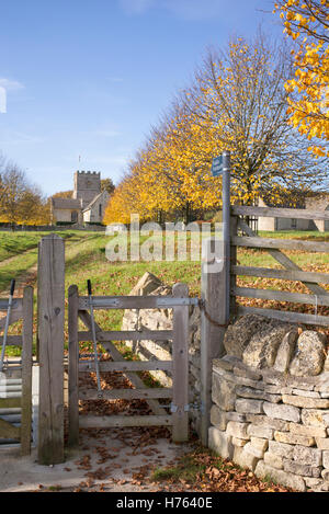 Öffentlichen Fußweg Zeichen und Tor zu St. Michael und alle Engel Kirche im Herbst. Guiting Power, Gloucestershire, England Stockfoto