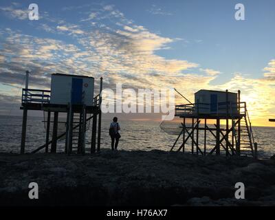 Frau zu Fuß am Strand zwischen zwei Fischer Hütten, Saint-Palais-Sur-Mer, Frankreich Stockfoto