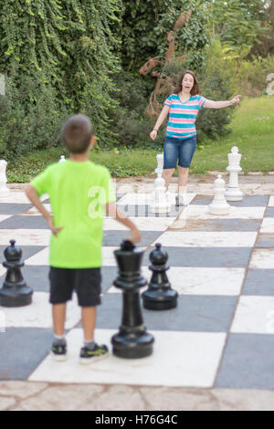 Bruder und Schwester Geschwister ein Spiel von riesigen Freiluft-Schachspiel mit großen Stücken in einem grünen Park im freien Stockfoto