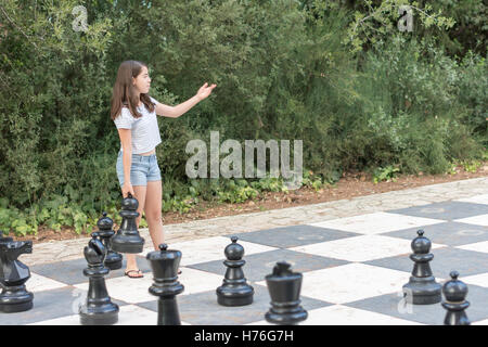 Teenager-Mädchen ein Spiel von riesigen Freiluft-Schachspiel mit großen Stücken in einem grünen Park im freien Stockfoto