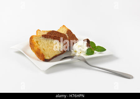 Scheiben aus Marmor Gugelhupf und Schlagsahne auf weißen Teller Stockfoto