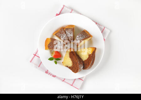 in Scheiben geschnitten Marmor Gugelhupf auf weißen Teller und kariertes Geschirrtuch Stockfoto