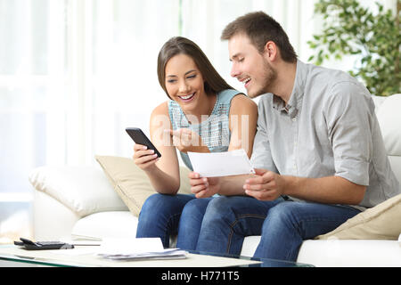 Paar Buchhaltung auf Linie mit einer Telefonanwendung Bank sitzen auf einer Couch im Wohnzimmer zu Hause tun Stockfoto