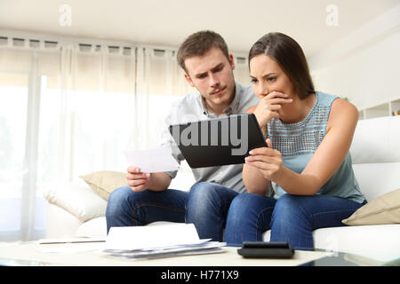 Besorgt paar Überprüfung Bankkonto Probleme in einer Tablette sitzen auf einer Couch im Wohnzimmer zu Hause Stockfoto