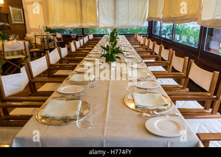 Langer Tisch in einem italienischen Restaurant mit formalen Platzeinstellung für ein Bankett. Stockfoto