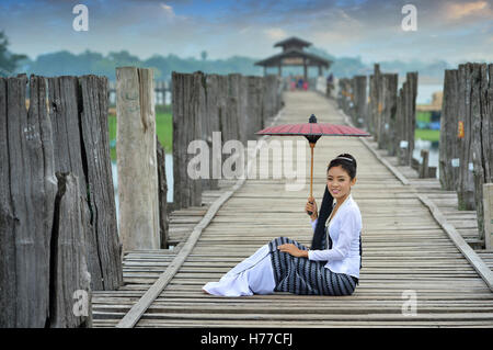 Porträt einer Frau sitzt auf der Brücke mit Sonnenschirm, Mandalay, Myanmar Stockfoto