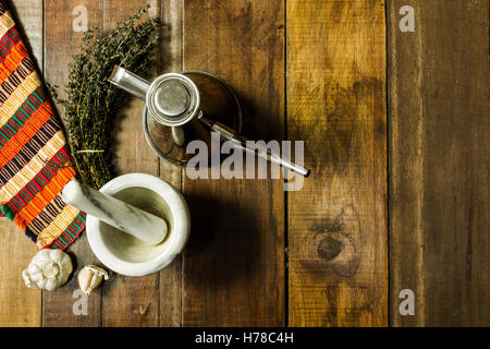 Luftaufnahme des Stilllebens Zutaten zum Würzen von Thymian, Knoblauch Ölkanne und einem Mörser auf einem rustikalen Holztisch Stockfoto
