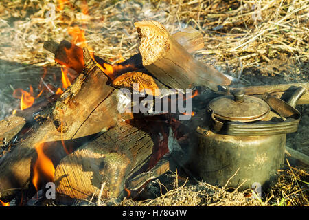 Auf eine Lichtung zündete ein Feuer in der Nähe von welche heizt ein Wasserkessel. Stockfoto