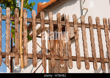 Fragment des alten geschnitzten hölzernen Zaun Nahaufnahme mit einem Weinstock und Haus hinter. Lazanias Dorf. Troodos. Zypern. Stockfoto