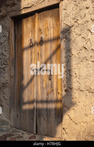 Alte braune schäbige Holztür mit rostigen Scharnieren am Eingang des alten zypriotischen Steinhaus. Lazanias Dorf. Zypern. Stockfoto