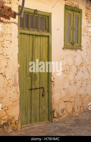 Alte grüne Holztür mit rostigen Scharnieren am Eingang des alten zypriotischen Steinhaus. Lazanias Dorf. Zypern. Stockfoto