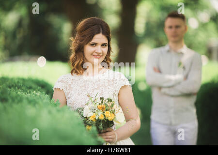 Braut posiert und lächelt während Bräutigam auf dem Hintergrund wartet Stockfoto