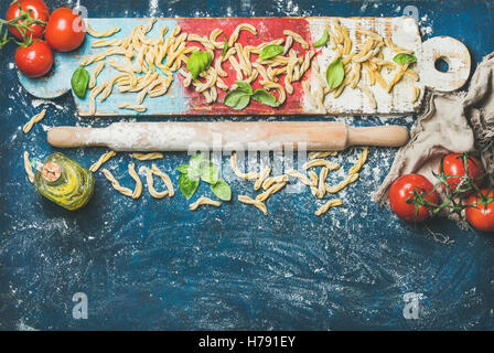 Frische Pasta Casarecce, Tomaten, Basilikum, Olivenöl auf bunten board Stockfoto