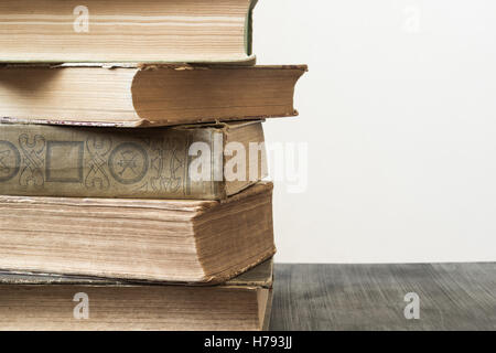Stapeln von alten Büchern über dunklen Holztisch vor weißen natürlichen Hintergrund