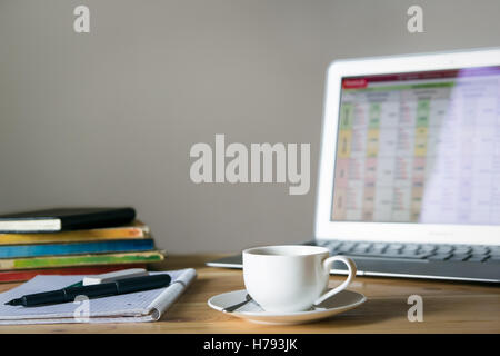 Home-Office Schreibtisch mit Laptop, Kaffee, Notizbücher und Bücher. Stockfoto