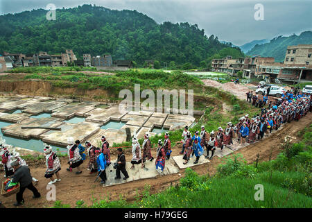 Nach die Parade, die, der Miao Mädchen und Frauen in traditionellen gekleidet gehen Kostümen wird wo die Tänze, während der Schwestern Essen Festival von Shidong in der Provinz Guizhou, China stattfinden Stockfoto