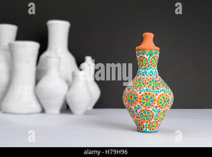 Stillleben mit einer dekoriert malte bunte Keramik Vase auf Hintergrund unscharf Gruppe von weiße Vasen Stockfoto