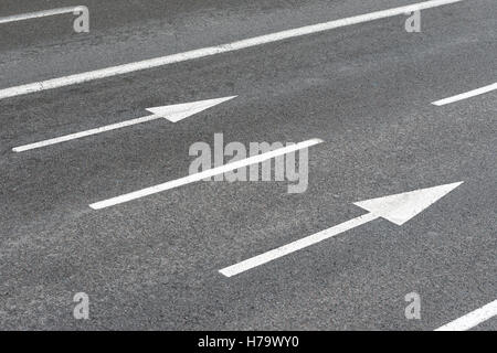 zwei weiße Pfeile Anzeichen auf eine städtische asphaltierte Straße Stockfoto