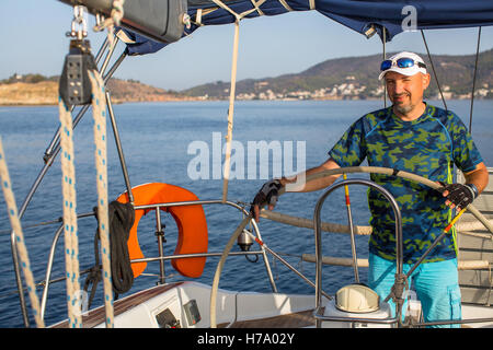 Mann-Skipper steuert Boot Segelyacht am Ägäischen Meer. Stockfoto